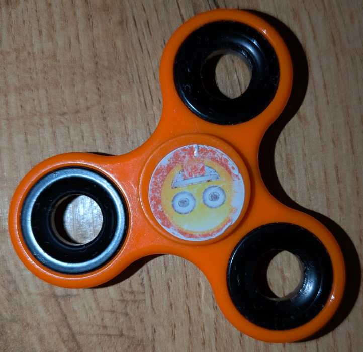 orange fidget spinner with smily sticker